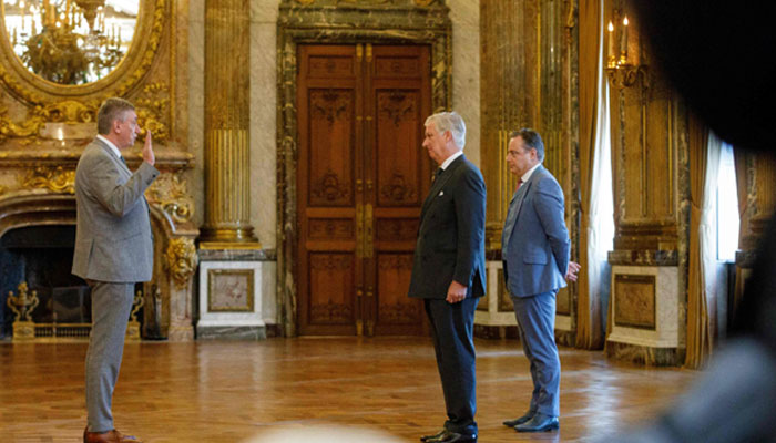 Vice-prime minister Jan Jambon raises his hand in front of Belgiums Prime Minister Bart De Wever and King Philippe - Filip of Belgium during the oath taking ceremony of the new Prime Minister and members of the federal government at The Royal Palace in Brussels on February 3, 2025.— AFP