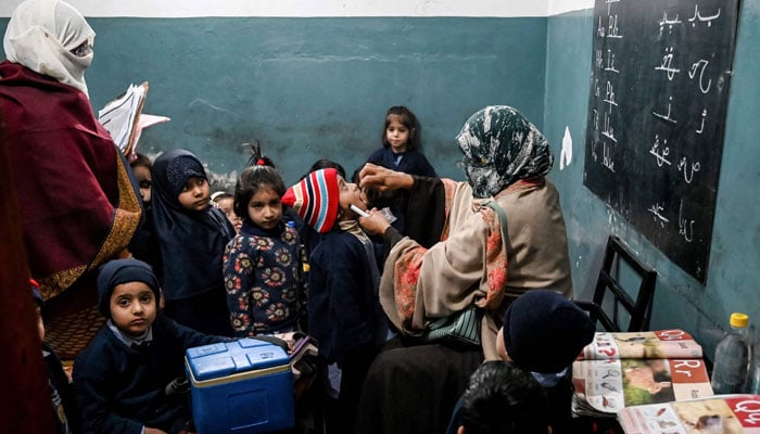 A health worker (right) administers polio drops to children at a school during a poliovirus vaccination campaign in Lahore on February 3, 2025. — AFP