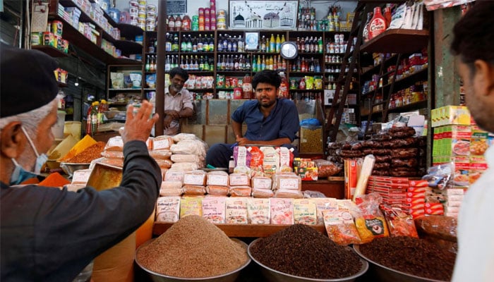 A shopkeeper listens to a customer as he sells groceries at a shop in a market in Karachi on June 10, 2022. — Reuters