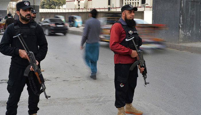 This image shows two police officials standing guard on a road. — AFP/File