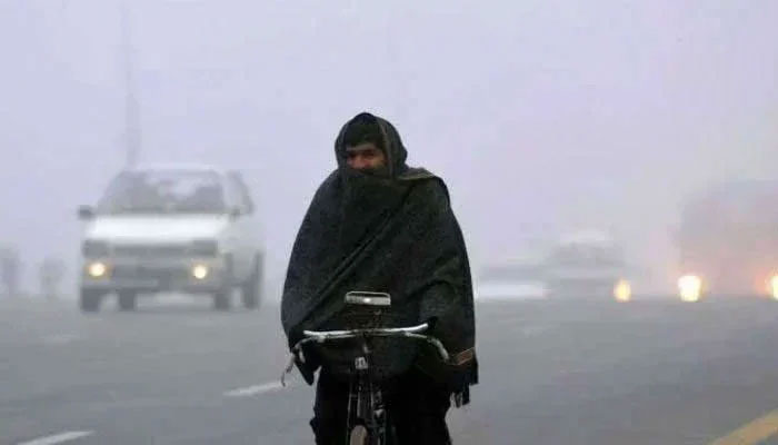 Representational image shows a man wrapped in a shawl cycles on a road in cold weather. — AFP/File
