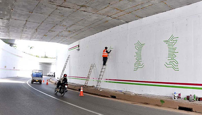 A painter busy making different designs on the wall of underpass. — APP/File