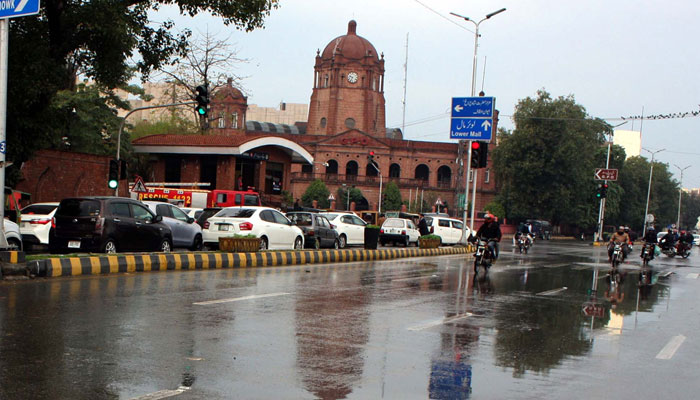 Commuters pass through a road during the downpour of winter season, at Mall Road in Lahore on February 20, 2025. — PPI