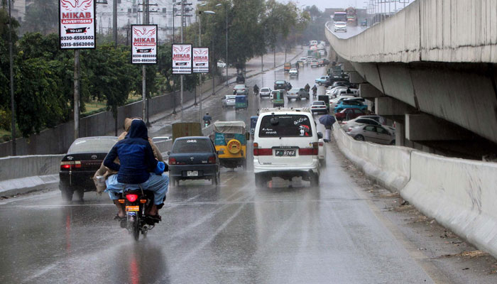 Commuters pass through the road during heavy downpours of the winter season in Peshawar on February 20, 2025. — PPI