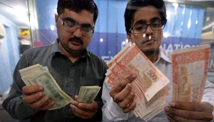 Two cashiers are seen counting currencies.— AFP/File