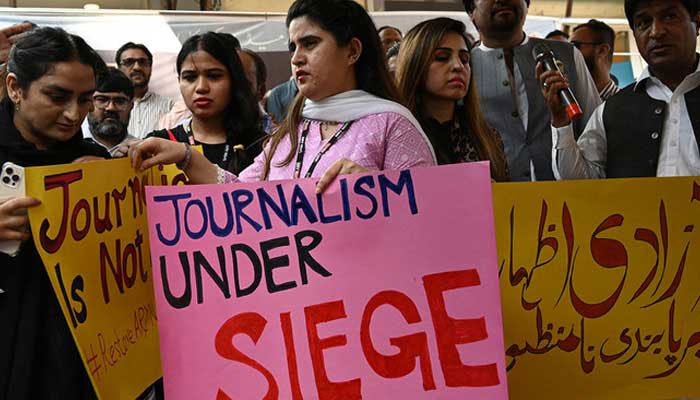 Journalists hold placards during a protest against a channel being taken off air. — AFP/File