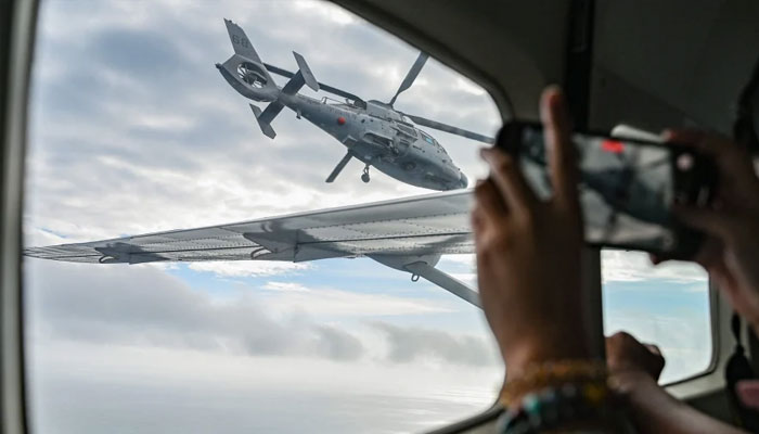 An aircraft identified by the Philippine Coast Guard as Chinese Navy helicopter (left) flies near the Bureau of Fisheries and Aquatic Resources (BFAR) plane during an aerial reconnaissance flight at Scarborough Shoal in the South China Sea. — AFP