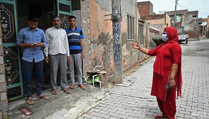 A woman speaks to a family during a coronavirus vaccine awareness campaign in Kalwa village, Haryana state, India. —AFP/File