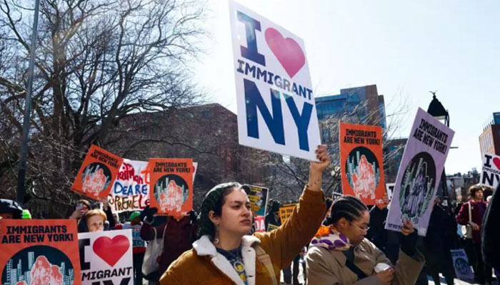 A demonstration in support of immigrants holding playcard in New York on February 22, 2025. —AFP