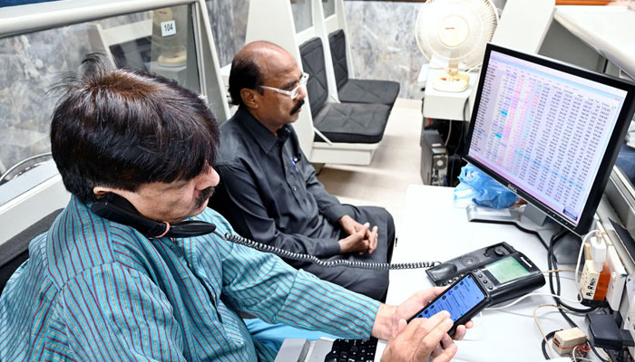Stock brokers attend to phone calls and monitor share prices on their computers during a trading session at the Pakistan Stock Exchange (PSX) in Karachi on December 4, 2024. — APP.