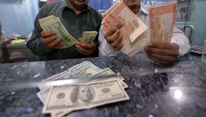 Money dealers count Pakistani rupees and US dollars at an currency exchanger in Islamabad. — AFP/File