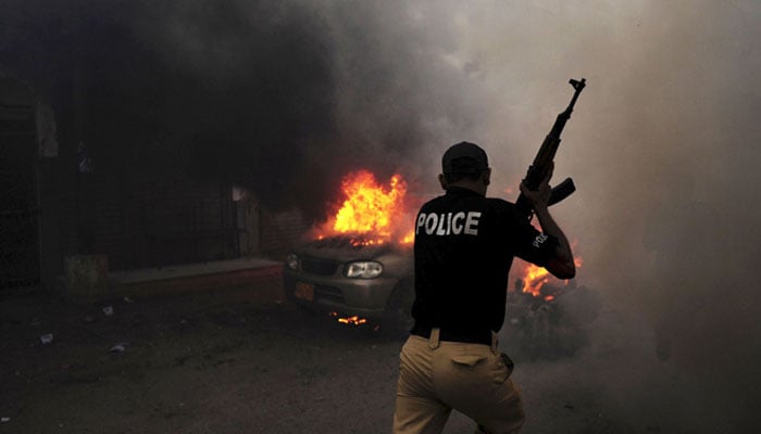This undated image shows a policeman running past a burning vehicle in Karachi. — AFP/File