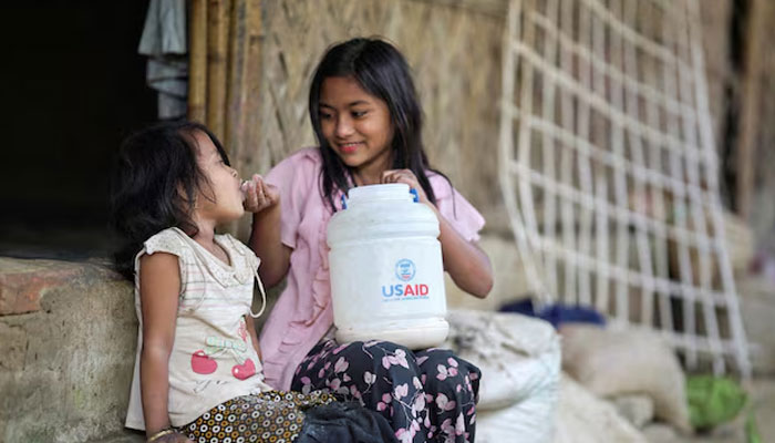 A Rohingya girl feeds a child from a jar with the USAID logo on it, at a refugee camp in Coxs Bazar, Bangladesh, February 11, 2025. —Reuters