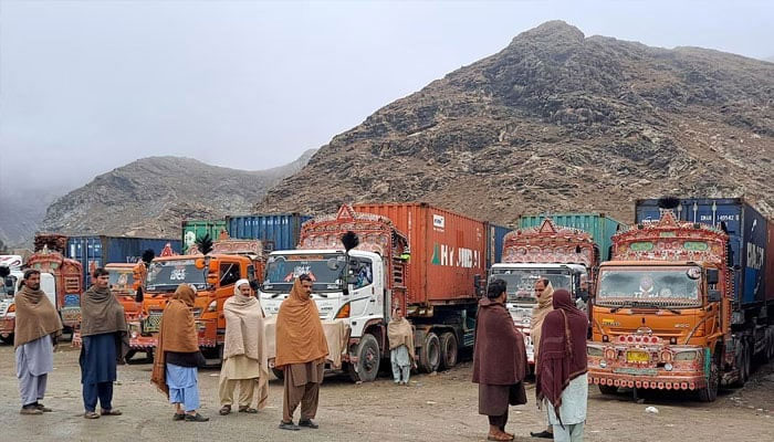 People stand next to parked trucks loaded with supplies at the Torkham border crossing following the closure of the border crossing between Pakistan and Afghanistan, March 3, 2025. — Reuters
