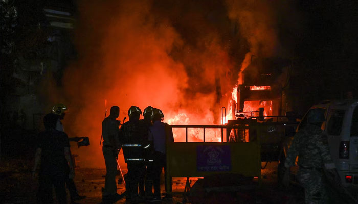 Members of police stand as vehicles burn after clashes erupted due to demands over removal of the tomb of Mughal emperor Aurangzeb, in Nagpur, India. —Reuters