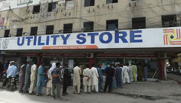 People stand in a queue outside a state-run utility store to buy groceries. — AFP/File