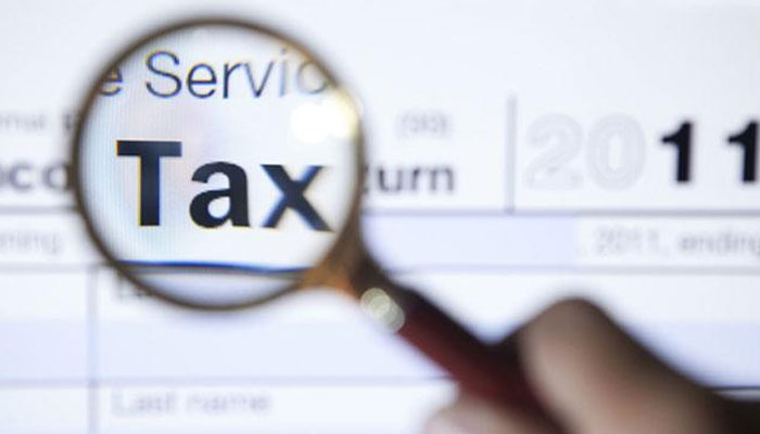 A person focusing word Tax with magnifire. —TheNews/File