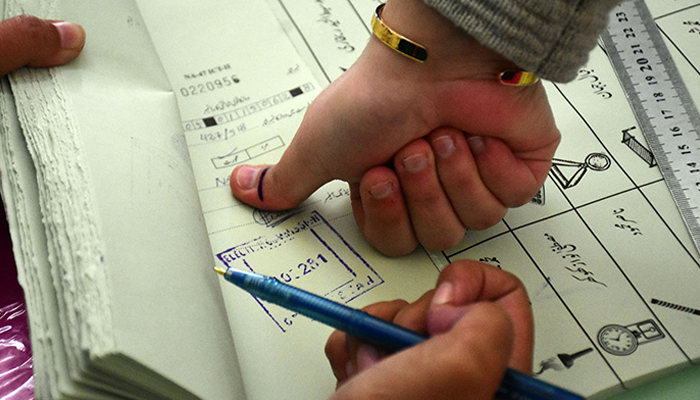Man puts his thumb impression on ballot book prior to issuance of a ballot paper to cast vote at a polling station in Islamabad during general elections on February 8, 2024. — Online