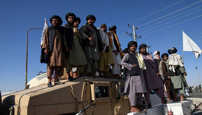 Taliban standing over an american militry vehicle. —AFP/File