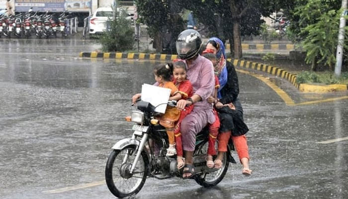A motorist is seen on his way along with his family during heavy rainfall in Lahore. — Online/File