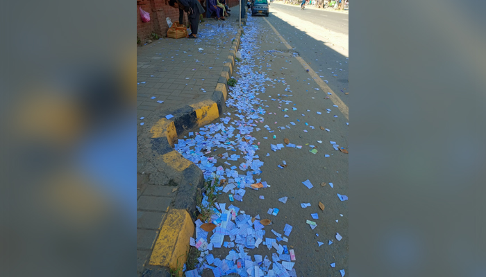 Papers from notebooks or textbooks can be seen torn on a road. — Facebook@shabbir.siddiq.5