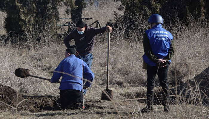 A war crimes prosecutor (right) and local residents exhume the remains of Olena Trofimova, 51-year-old, killed on June 25, 2022 during the Russian invasion, at the cemetery of Davydiv Brid, near Kherson, southern Ukraine, on Feb. 16, 2023. —AFP