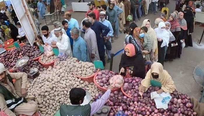 People stand in long queues to buy vegetables from a vendor at Ramadan Sasta Bazaar in Punjab. — Online/File