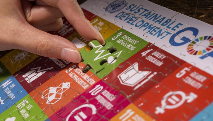 A person solving puzzle on SDGs board. — UN website/File