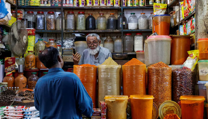 A shopkeeper speaks with a customer while selling spices at a market in Karachi on June 11, 2024. — Reuters