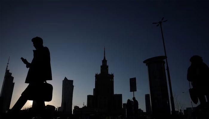 Silhouettes of people walking are seen in front of the communist-era Palace of Culture and Science in the centre in Warsaw, April 2, 2025.—Reuters