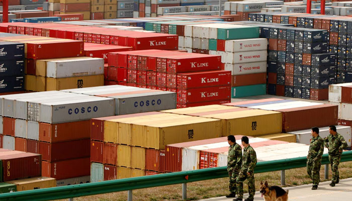 Security guards walk past containers at a port in Shanghai March 8, 2009. —Reuters