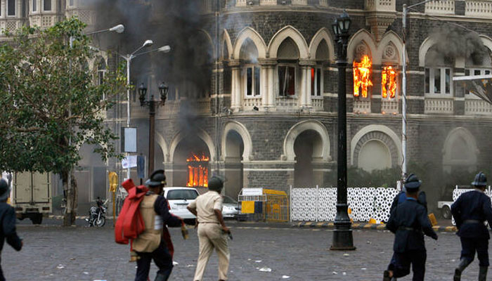 In this file photo, taken on November 29, 2008, policemen and firefighters run in front of the burning Taj Mahal hotel during a gunbattle in Mumbai. — Reuters
