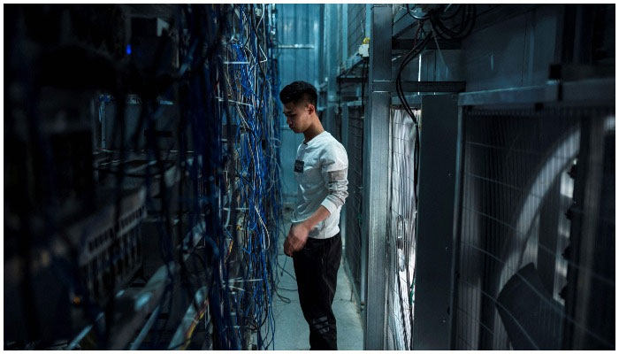 This file photo taken on April 1, 2021 shows a worker adjusting cryptocurrency mining rigs at a cryptocurrency farm in Dujiangyan in Chinas southwestern Sichuan province.—AFP
