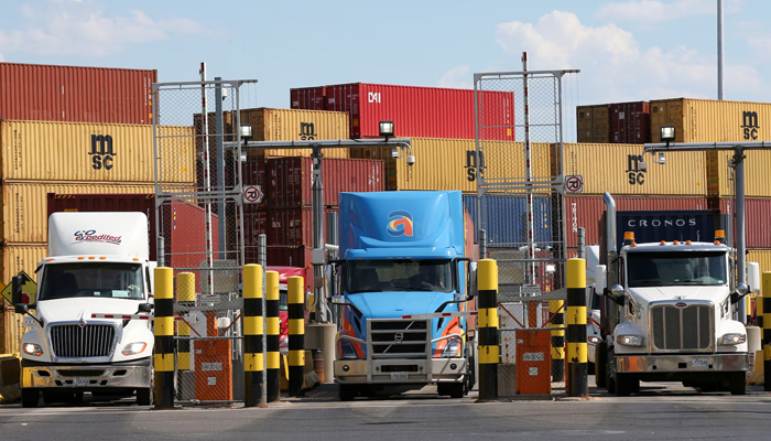 Trucks loaded with shipping containers leave a port. — Reuters