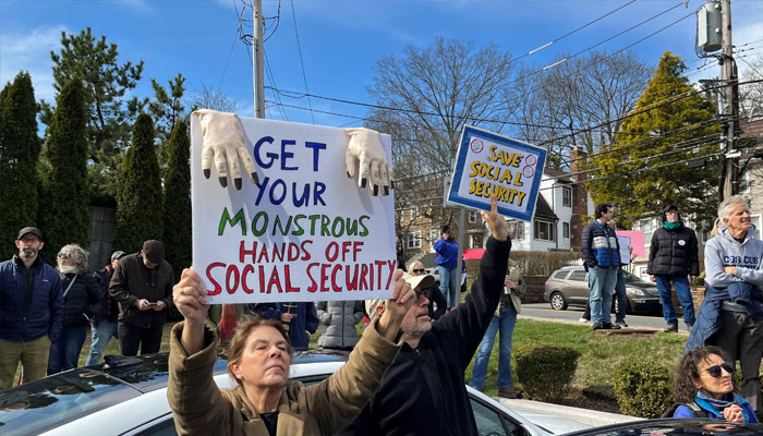 People hold signs during a protest against cuts made by Trumps administration to the social security, in White Plains, New York, on 22 March 2025. — Reuters