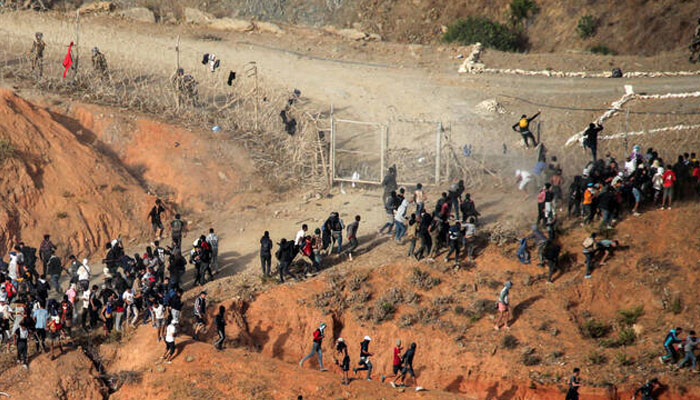 Migrants storm a barbed-wire fence as they attempt to cross the land border with Spains African enclave of Ceuta near Fnideq in northern Morocco on September 15, 2024. —AFP/File