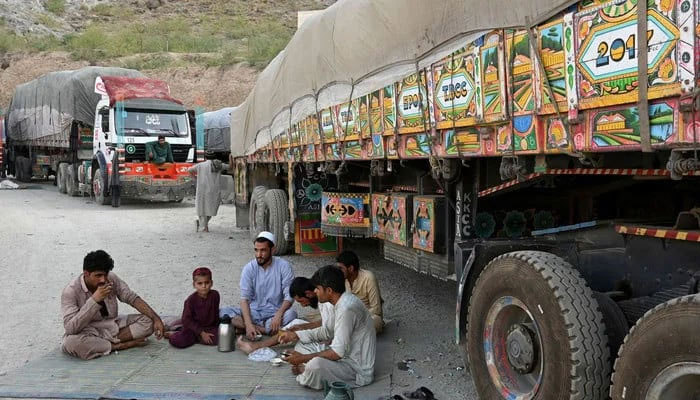 Drivers along with a boy drink tea next to trucks parked along a road in KP. — AFP/File