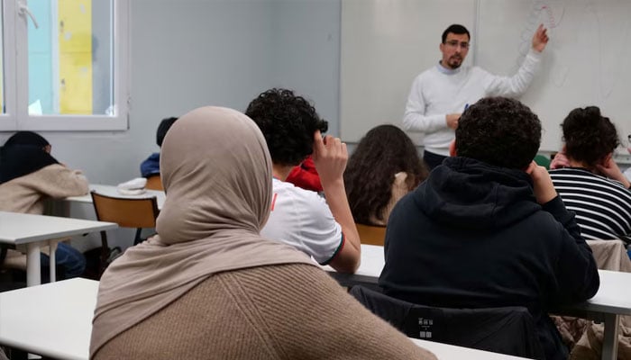Middle school students, some wearing a hijab, listen to teacher Ilyas Laarej during an Islamic ethics class at the Averroes school, Frances biggest Muslim educational institution that has lost its state funding on grounds of administrative failures and questionable teaching practises, in Lille, France, March 19, 2024.—Reuters