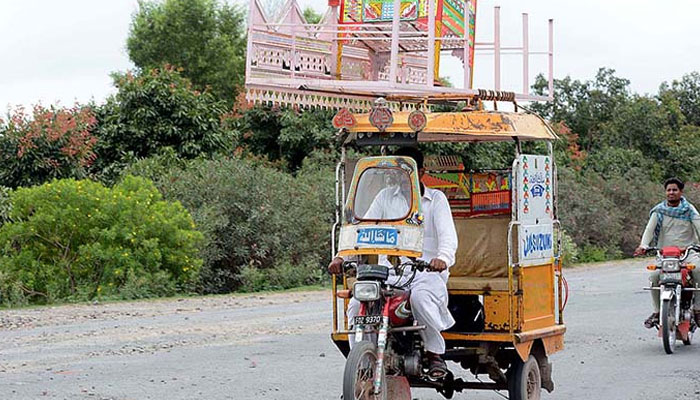 A view of motorcycle rickshaw on the way carrying goods on rooftop. — APP/File