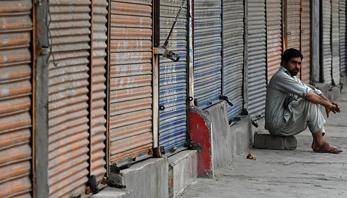 A man sits near a closed market, during a shutter down and wheel-jam strike. — Reuters/File