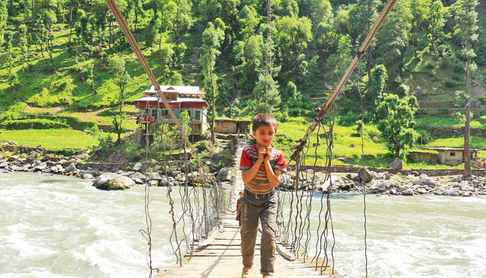 A boy crossing a wooden bridge in AJK. —TheNews/File