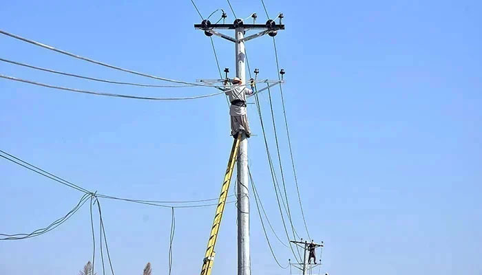 Workers are seen on an electric pole in Islamabad on October 26, 2023. — APP