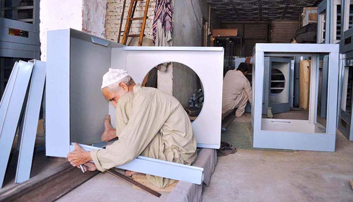 A worker is making water air room cooler in his work shop at Porani Pull satellite town. — APP/File