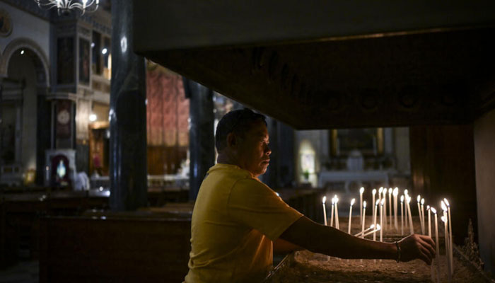 A worshiper lighting candles in a church. —AFP/File