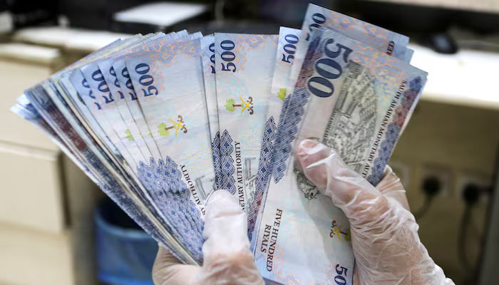 A Saudi money exchanger wears gloves as he counts Saudi riyal currency at a currency exchange shop in Riyadh, Saudi Arabia March 10, 2020. — Reuters