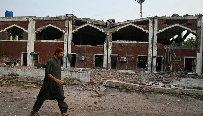 A resident walks in front of a damaged building at the Government Health and Educational complex in Muridke about 30 kilometres from Lahore, on May 7, 2025, after Indian strikes. — AFP