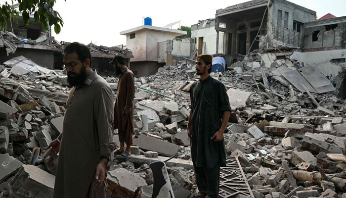 Locals stand on the debris of destroyed structures at the Government Health and Educational complex in Muridke about 30 kilometres from Lahore, on May 7, 2025, after Indian strikes. — AFP