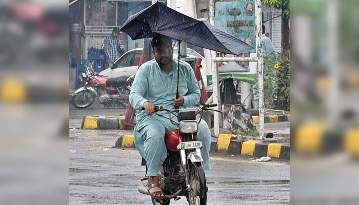 A motorcyclist uses an umbrella to protect himself from the rain experienced in the city on May 8, 2025. —APP