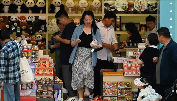 People visit a shop along a busy street in Beijing. —AFP/File