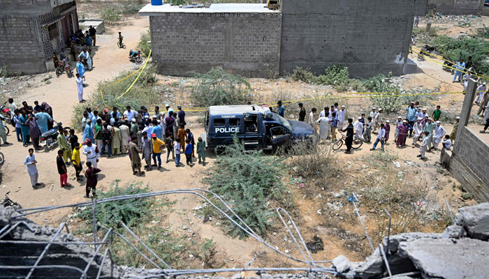 This representational image shows residents gather as police personnel inspect the site where an alleged drone was shot down in Karachi on May 8, 2025. — AFP
